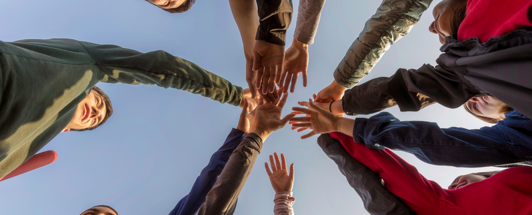 Staff members putting their hands in the middle of the circle. 